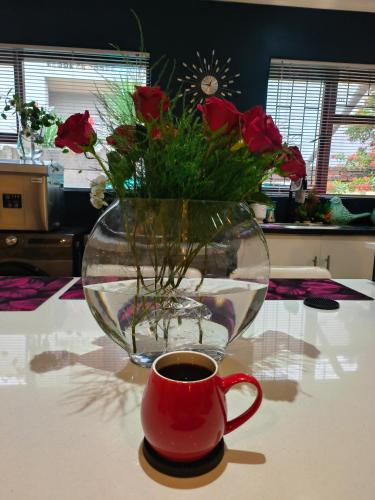 a vase of roses and a cup of coffee on a table at Hidden Gem RUWARI in Cape Town