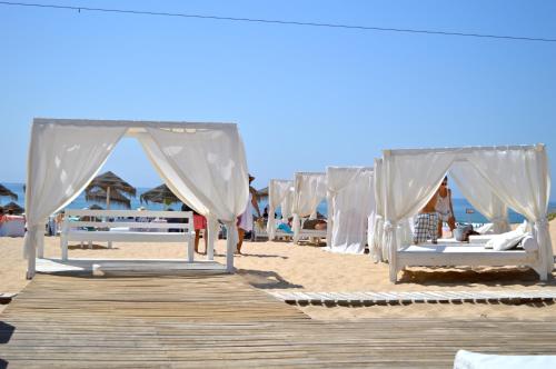 a row of beds on a beach with a boardwalk at Apartment Qiu in Costa da Caparica