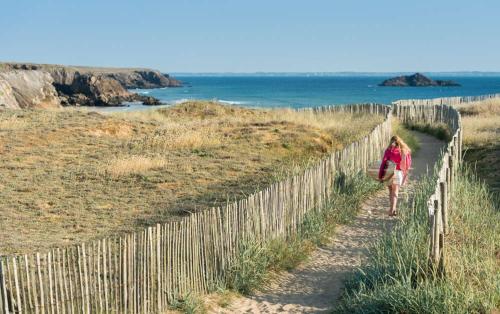 a woman walking along a fence at the beach at Maison 3 chambres 250 m de la mer in La Trinité-sur-Mer