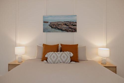 a bedroom with a white bed with two lamps at Casa Agonis in Geographe