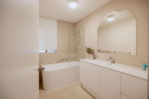 a white bathroom with a tub and a sink and a mirror at Casa Agonis in Geographe