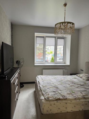 a bedroom with a bed and a television and a chandelier at Апартаменти новобудова Львів in Lviv