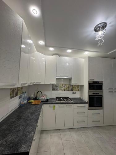 a kitchen with white cabinets and a black counter top at Апартаменти новобудова Львів in Lviv