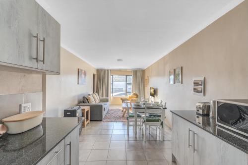 Una cocina con una mesa y una sala de estar. en Airville Luxury Apartments, 7min Drive to Cresta Mall, en Johannesburgo