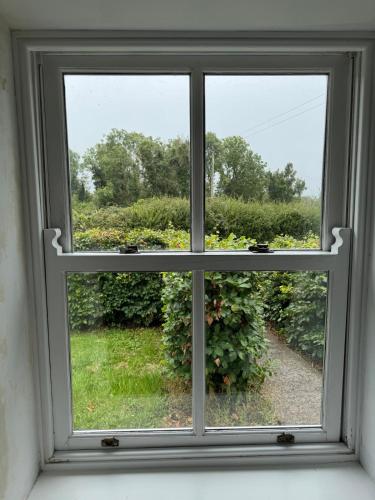 a window with a view of a garden at The Rose & Pearl Retreat in Ballintober