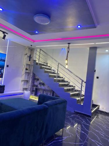 a living room with a blue couch and stairs at Manor Apartment in Lekki