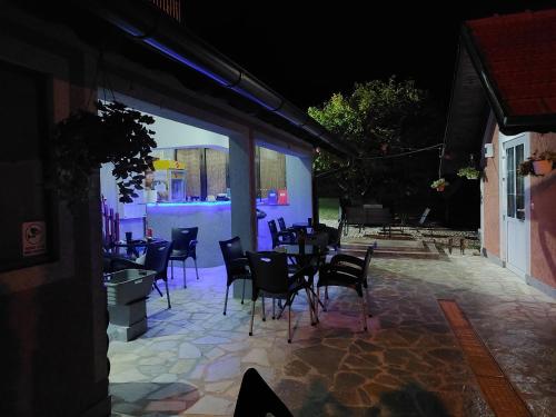 a patio with chairs and tables at night at Djokic 2 in Soko Banja