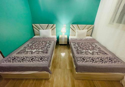 two beds in a room with green walls at Farida Pyramids ŌTEL in Cairo