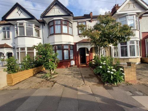 a large white house with a tree in front of it at Cosy City Retreat in Ilford