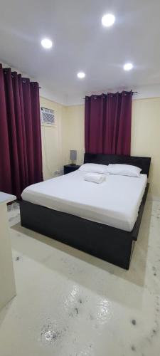 a bedroom with a large bed with purple curtains at Oceanview Suites in Saint Georgeʼs
