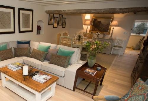 a living room with a white couch and a table at Craigmoor Cottage, enchanting, tranquil & central in Bourton on the Water