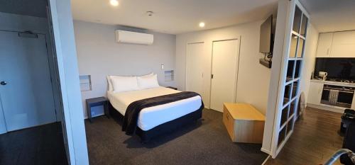 a small bedroom with a bed and a kitchen at Lakefront Lodge Taupo in Taupo