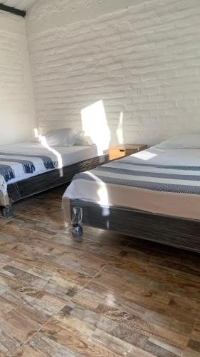 two twin beds in a room with wooden floors at EcoPolis el queremal entrada in Papagalleros