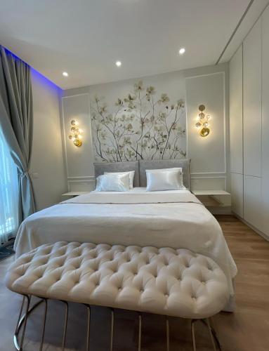 una camera da letto con un grande letto bianco con una panca imbottita di Enrik a Tirana