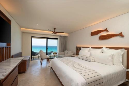 a bedroom with a large bed and a dining room at Secrets Mirabel Cancún Resort & Spa in Cancún
