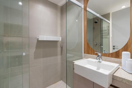 a bathroom with a sink and a glass shower at Skyline Parque Moinhos by LikeHome in Floresta