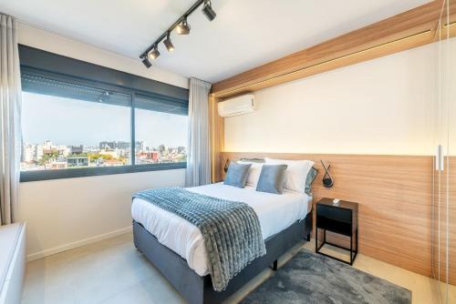 a bedroom with a bed and a large window at Skyline Parque Moinhos by LikeHome in Floresta