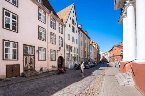 a person standing on a cobblestone street with buildings at 15th Century Flat with Parking, High Ceilings in Tallinn