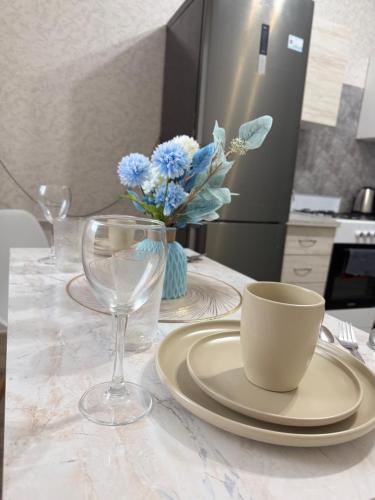 a table with a plate and a cup and a glass at Уютная новая квартира в ЖК Береке 2 рядом с Kostanay Plaza in Kostanay