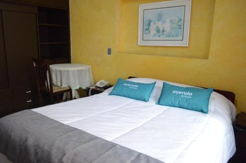 a bed with two blue pillows on top of it at Hotel Calle 112 in Bogotá