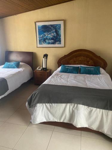 a bedroom with two beds with blue pillows at Hotel Calle 112 in Bogotá