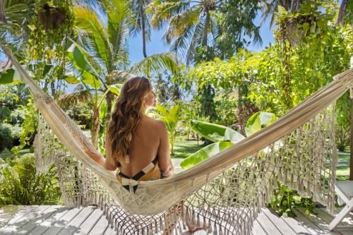 a woman sitting in a hammock in a resort at Pousada Pais Tropical in Icaraí
