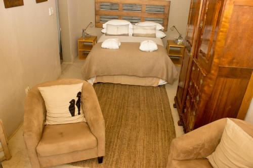 a hotel room with two beds and a chair at The Ibis Lounge in Nieu-Bethesda