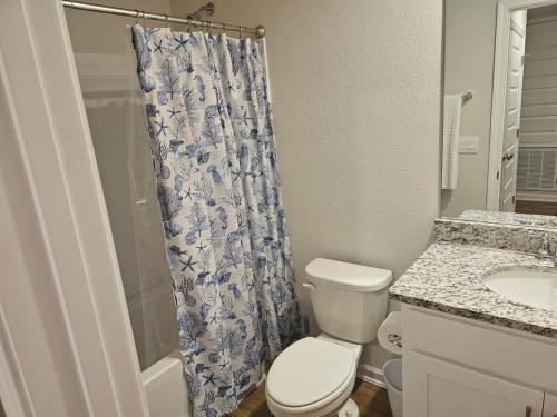 a bathroom with a toilet and a shower curtain at Brand new Townhouse in Orange Beach