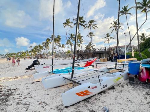 a group of boats on a beach with palm trees at SOL CARIBE VILLAGE - STUDIOS DELUXE - playa LOS CORALES in Punta Cana