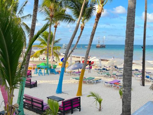 a beach with chairs and palm trees and the ocean at SOL CARIBE VILLAGE - STUDIOS DELUXE - playa LOS CORALES in Punta Cana