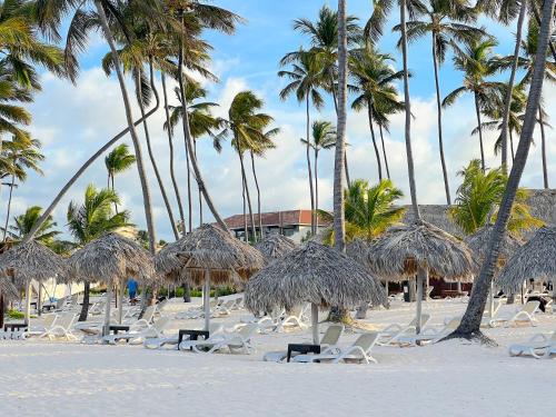 a group of chairs and palm trees on a beach at SOL CARIBE VILLAGE - STUDIOS DELUXE - playa LOS CORALES in Punta Cana