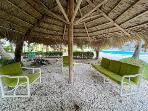 a patio with a couch and chairs under a straw umbrella at SOL CARIBE VILLAGE - STUDIOS DELUXE - playa LOS CORALES in Punta Cana
