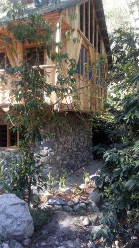 a building with a stone wall and a balcony at Glamping Machupicchu Lodge in Santa Teresa