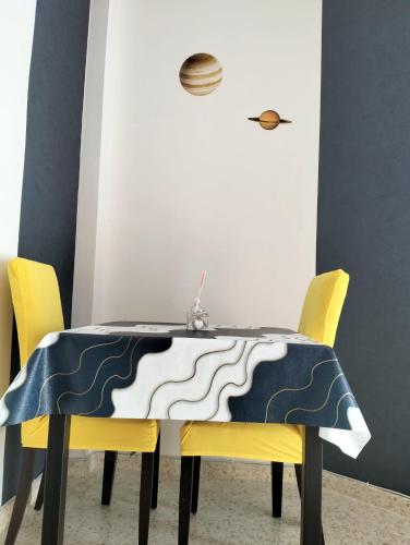 a dining room table with yellow chairs and a blue and white table cloth at Studio Nova in Priego de Córdoba