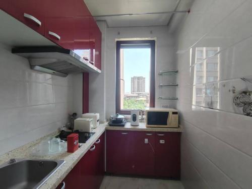 a kitchen with red cabinets and a sink and a window at Central Street Apartment 1 in Harbin