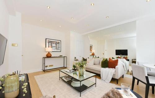 a living room with a couch and a table at Estatesmen Harrods Knightsbridge Apartment in London