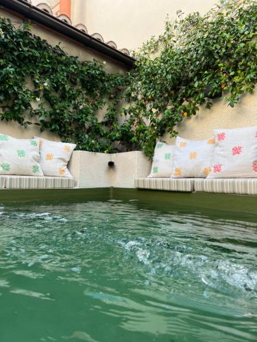 a pool of water with pillows and plants on a building at La Casa del Pasadizo elegante casona restaurada con piscina in Oropesa