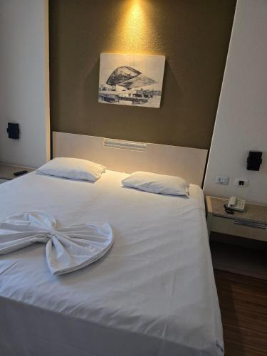 a white bed with a bow on top of it at Flat Ambassador in Curitiba