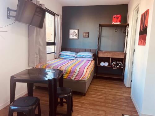 a small bedroom with a bed and a table at Studio charmoso no coração de Curitiba! in Curitiba