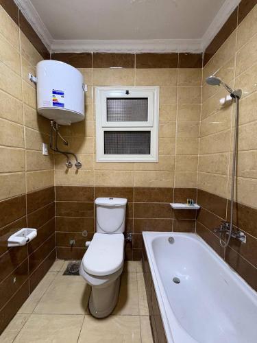 a bathroom with a toilet and a tub and a window at Sneferu Pyramids View in Cairo