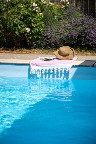 a hat sitting on a towel next to a swimming pool at Calme et confort en Charente , Gîte Les Vignes avec piscine in Saint-Médard