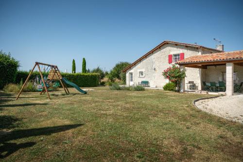 a yard with a swing set and a house at Calme et confort en Charente , Gîte Les Vignes avec piscine in Saint-Médard