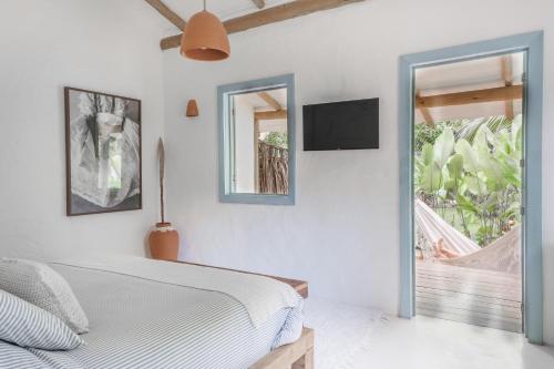 a bedroom with a bed and a tv on the wall at Vila Oyá - Praia de Algodões in Marau