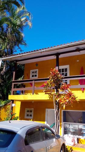 a car parked in front of a yellow building at SUITES E CHALES PRIVADOS Rock's&Rose's home in Camburi
