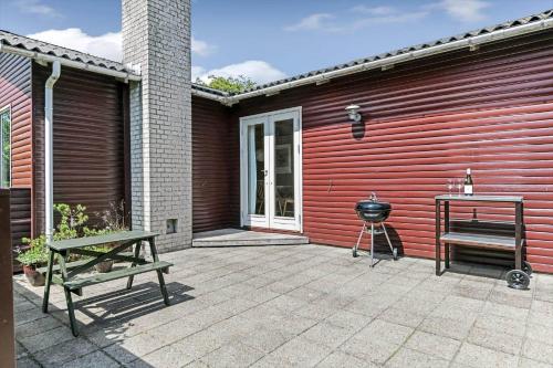a patio with a grill and a b smoker next to a red wall at BV310-Blavand-Gronnevej-16 in Blåvand
