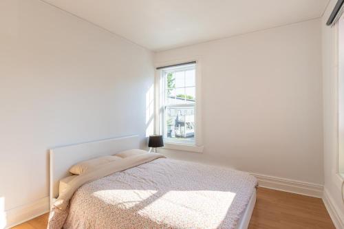 a white bedroom with a bed and a window at Chez Flo in Trois-Rivières