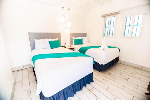 two beds in a hotel room with green and white at Hotel Casa Turquesa in Flores
