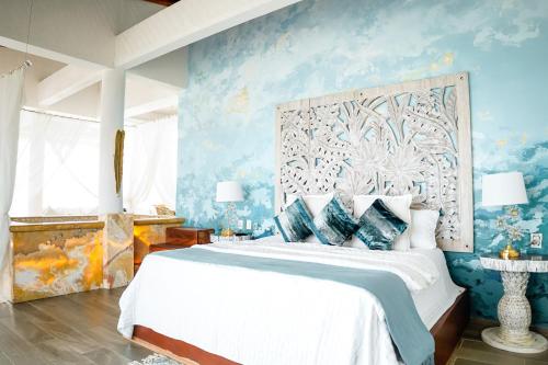 a bedroom with a large bed with blue walls at Muúnek Hotel Boutique Art & Spa, adults only in Barra Vieja