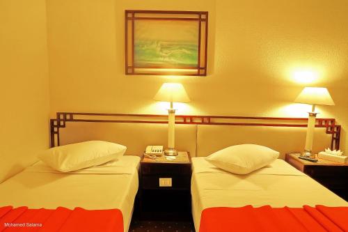 two beds in a hotel room with two lamps at Resta Port Said Hotel in Port Said