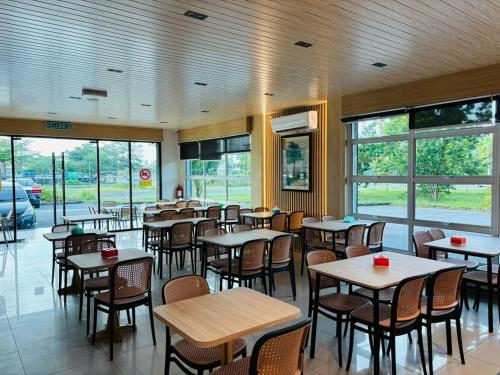 a dining room with tables and chairs and windows at Chemara Boutique Hotel in Miri